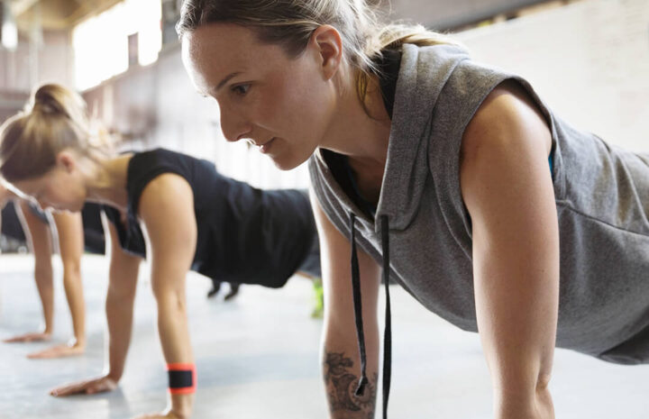 grupa początkujących wykonuje różne ćwiczenia CrossFit w jasnej sali treningowej
