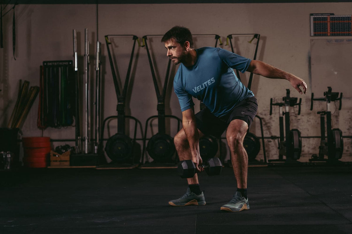 kobieta machająca ciężkim kettlebell w swingach obok lustra w siłowni
