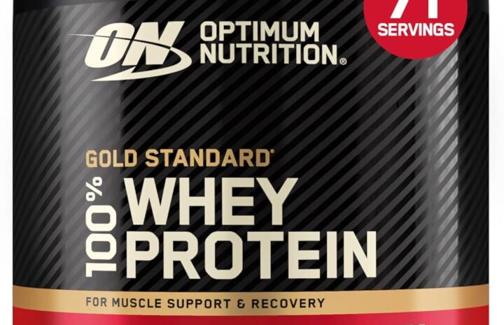 Różnokolorowe opakowania protein serwatkowych obok shakera i owoców na stole